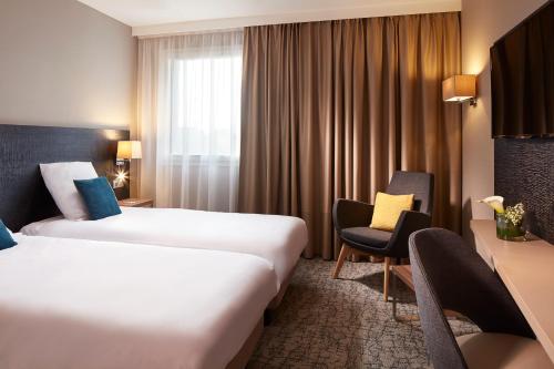 科尔马科尔马中心安特林登美居酒店的酒店客房,配有两张床和椅子