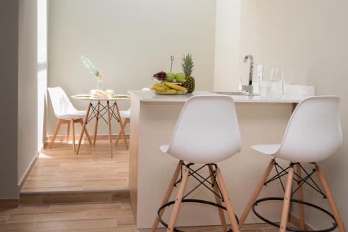 玛利亚Riaki Apts的厨房配有2张白色吧台凳和1个柜台
