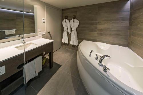 魁北克市Hôtel & Suites Normandin Québec的带浴缸、水槽和镜子的浴室