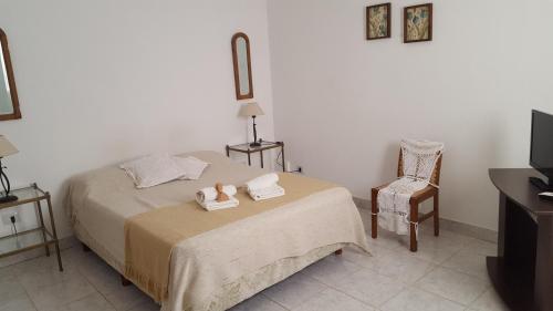 乌拉圭河畔康塞普西翁Antigua Fonda Hosteria的一间卧室配有带毛巾和椅子的床