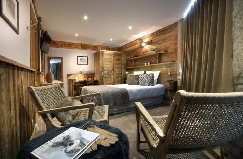 葱仁谷Hotel 3 Vallées Val Thorens的配有床、椅子和桌子的酒店客房