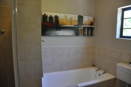 塞吉菲尔德Sedgefield Island Villa的带浴缸的浴室和墙上的绘画