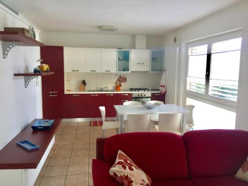 阿科Gardasol Holiday Apartment的一间带红色沙发的客厅和一间厨房