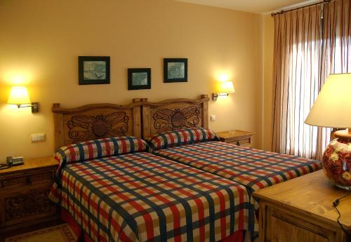 纳瓦雷东达德格雷多斯Hotel Garabatos的一间卧室配有一张床、一张桌子和一盏灯