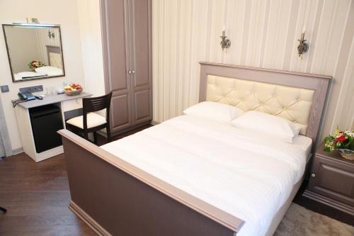 阿拉木图D'拉米酒店的卧室配有一张大白色的床和书桌