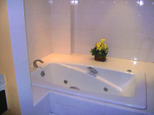 蒙特雷勒噶尔酒店的浴室里设有白色浴缸,花瓶装有花卉