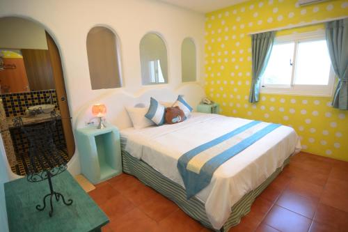 鹅銮鼻加利利民宿的一间卧室配有一张带黄色波卡点的大床
