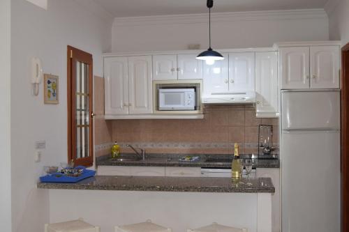 卡门港唐拉斐尔酒店的厨房配有白色橱柜和白色冰箱。
