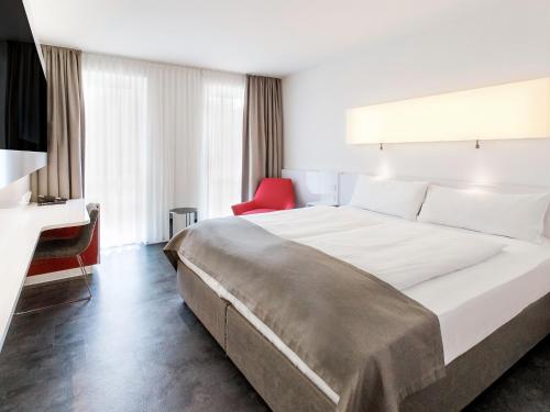 美因河畔法兰克福法兰克福多梅洛酒店的酒店客房设有一张大床和一张红色椅子。