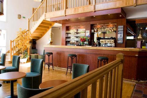 米萨讷Hotel ARBOR - Les Hunaudieres - Le Mans Sud - Mulsanne的餐厅内带绿色桌椅的酒吧