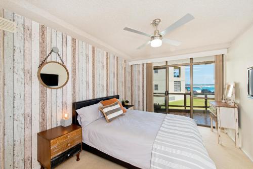 麦夸里港Beauty at the Beach - modern beachfront apartment的一间卧室配有一张床、镜子和窗户
