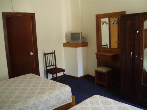 库里亚盘扫洛伦索酒店的一间卧室配有一张床、梳妆台和镜子