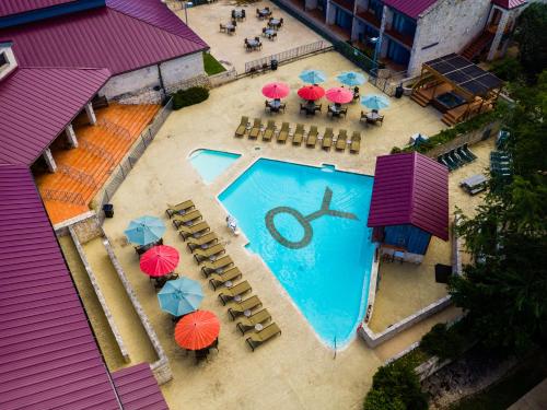克尔维尔Y O Ranch Hotel and Conference Center的享有带遮阳伞和桌子的游泳池的顶部景致
