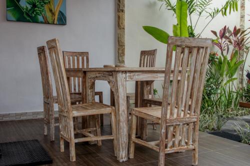 坎古Nyoman Guesthouse Berawa Canggu的一张木桌、四把椅子和一张桌子及椅子
