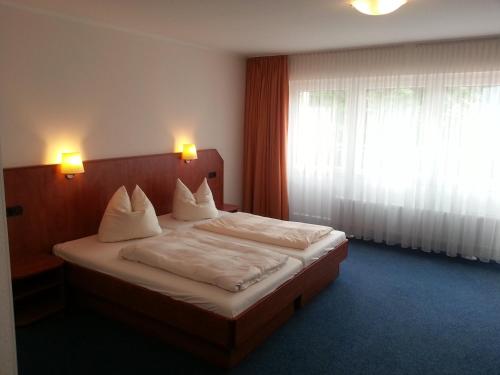 汉恩明登Schmucker Jäger - Hotel Garni的一间卧室配有一张带白色床单的床和一扇窗户。