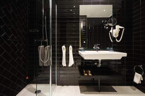 多列毛利诺斯Costa del Sol Torremolinos Hotel的黑色瓷砖浴室设有水槽和淋浴