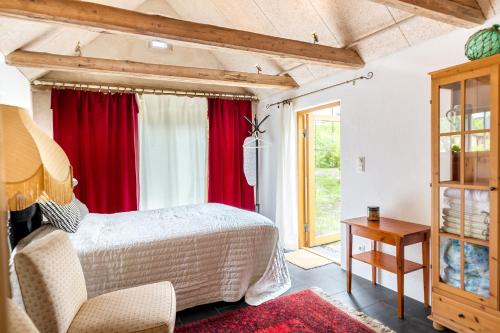 Sankt OlofLitet Gästhus i Sankt Olof的一间卧室配有红色窗帘、一张床和一张桌子