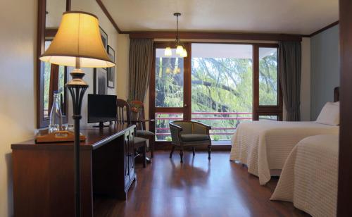 危地马拉君悦太阳酒店的酒店客房配有一张床和一张带台灯的书桌