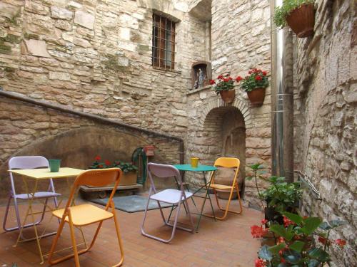 阿西西Camere Santa Chiara的石头建筑中带桌椅的庭院