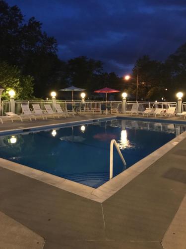 五月岬郡Cape Harbor Motor Inn的夜间游泳池,配有椅子和遮阳伞