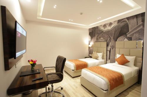 新德里Kaisons Inn (Near Apollo Hospital)的酒店客房设有两张床、一张桌子和一台电视。