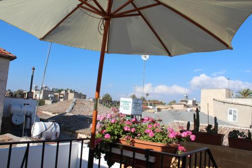 北尼科西亚Pedieos Guest House的阳台上的桌子上摆放着雨伞和鲜花