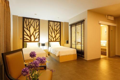 Ban Khi Sua绿点公寓酒店的一间卧室设有两张床和一张紫色花卉桌子。