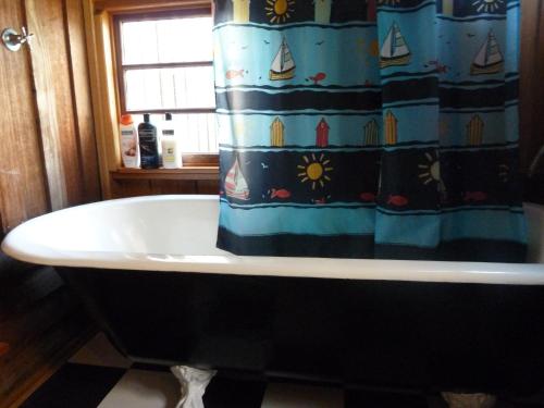 Hastings牡蛎山林小屋的浴室设有带浴帘的浴缸
