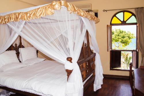 桑给巴尔Abuso Inn的一间卧室设有天蓬床和2个窗户