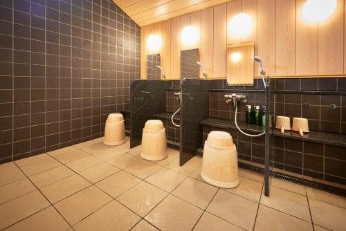 本庄市本庄早稻田站前坎拉库酒店的浴室设有3个小便池、3个盥洗池和淋浴。