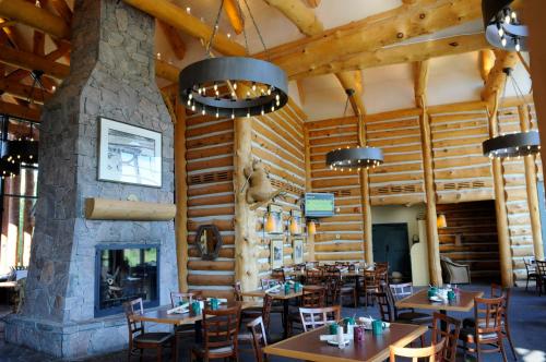 MacTier洛基洪峰高尔夫度假酒店的餐厅设有木墙、桌子和壁炉