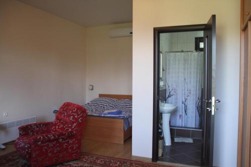 古达乌塔АМРАПХА的一间卧室配有一张床和一张红色椅子