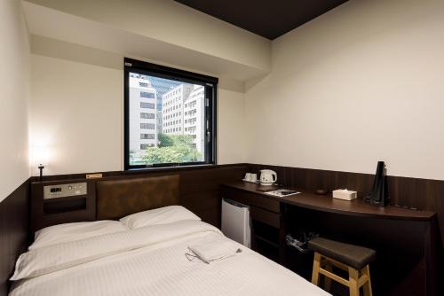 东京东京贝尔肯酒店的一间卧室配有一张床、一张书桌和一个窗户。