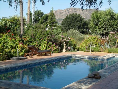 阿洛拉白色公寓的花园内的游泳池,花园内有长凳和鲜花