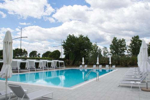 塞萨洛尼基麦卡德尼娜皇宫酒店的一个带躺椅和遮阳伞的游泳池