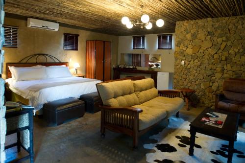 布隆方丹Emoya Basotho Lodge的一间卧室配有一张床、一张沙发和一把椅子