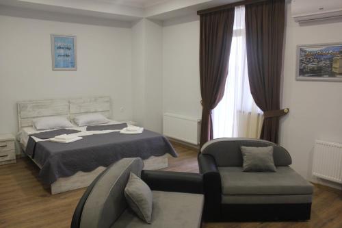 第比利斯Apart Hotel Vera的一间卧室配有一张床、一把椅子和一张沙发
