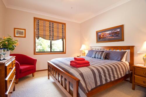 奥兰治Clifton Gardens Bed & Breakfast - Orange的一间卧室配有一张床和一张红色椅子