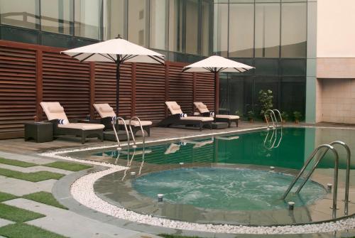 大诺伊达大诺伊达萨沃伊套房酒店的一座带椅子和遮阳伞的游泳池位于一座建筑旁边