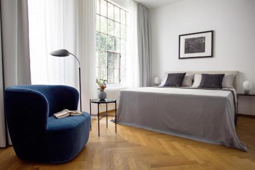汉堡八月公寓的一间卧室配有一张床和一张蓝色椅子