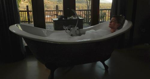 马迪克韦狩猎保护区Etali Safari Lodge的坐在一个房间里浴缸里的女人