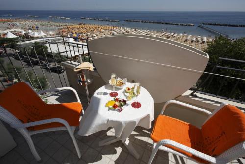 里米尼依赛德凯达酒店的海滩景阳台配有桌椅