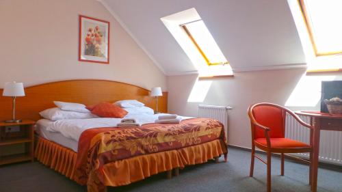 科马罗姆坲拉斯酒店的卧室配有1张床、1张桌子和1把椅子