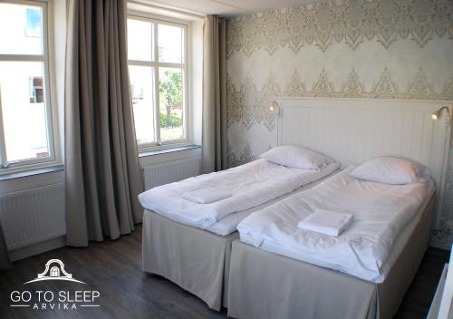 阿尔维卡Go to sleep Arvika的一间卧室配有两张带白色床单的床和两个窗户。