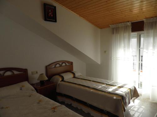 阿兰扎达Novas Foxos (Ático)的一间卧室设有两张床,窗户配有窗帘