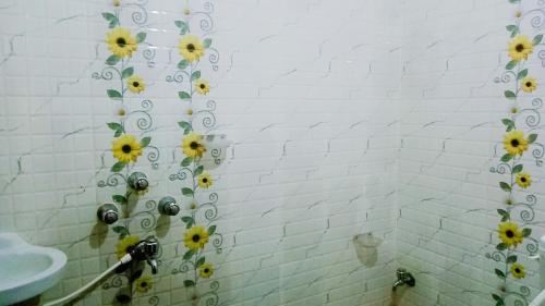 普里Shradharam Lodge的浴室设有黄色花卉的浴帘