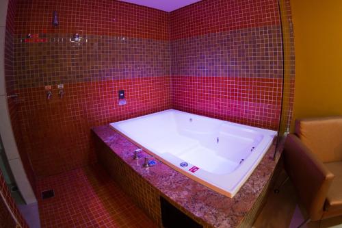 福塔莱萨Platinum Motel (Adults Only)的带浴缸的红色瓷砖浴室和红色瓷砖墙