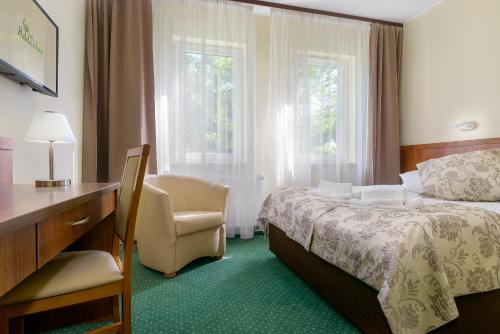 波兹南泽罗尼酒店的一间卧室配有一张床、一张桌子和一把椅子