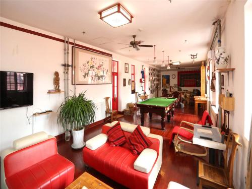 青岛青岛麦子青年旅社的客厅配有红色沙发和台球桌