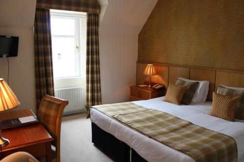 伦丁林克斯老庄园酒店的配有一张床、一张书桌和一扇窗户的酒店客房